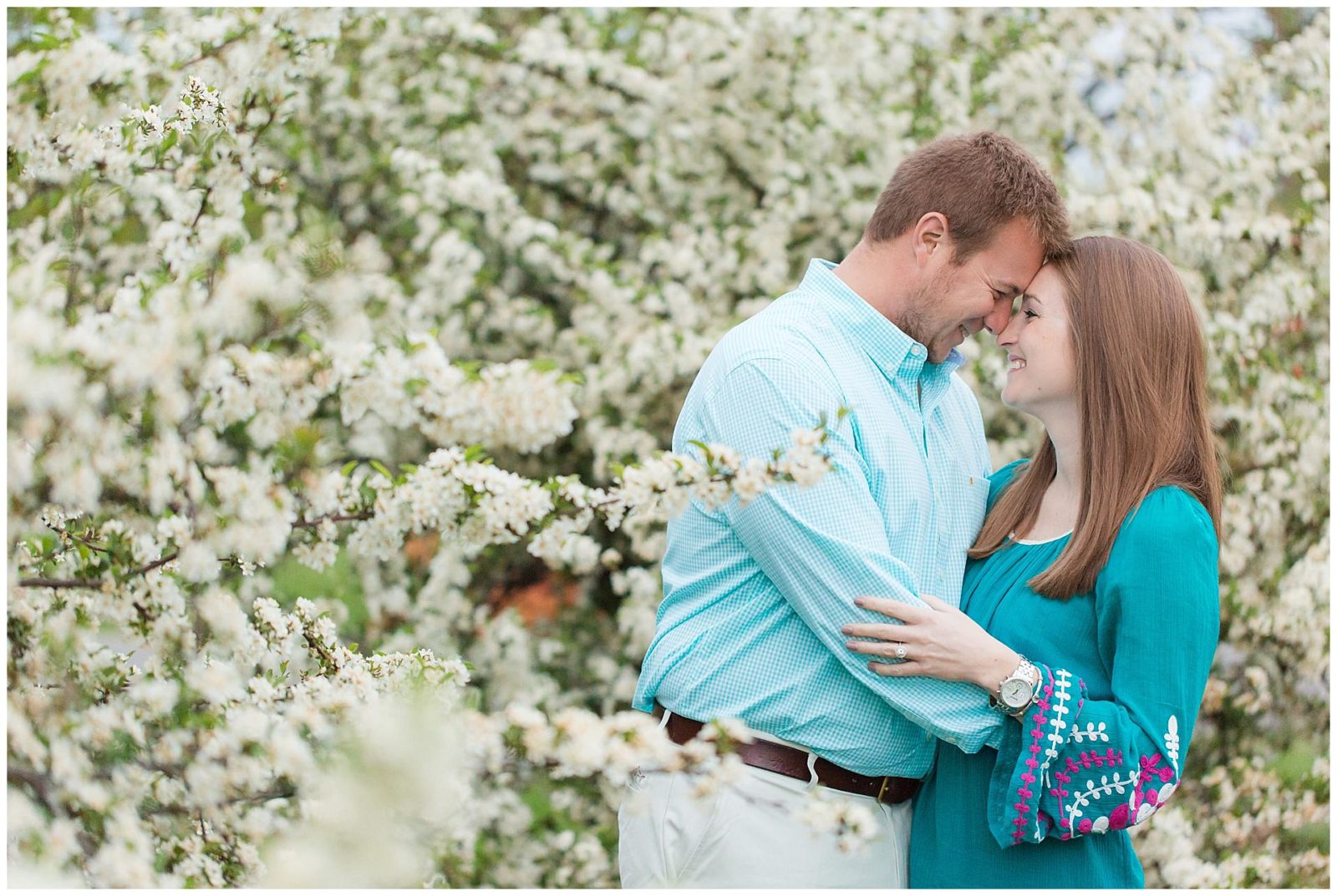 Couple surrounded by blooming trees during their engagement session at the University of Kentucky Arboretum.