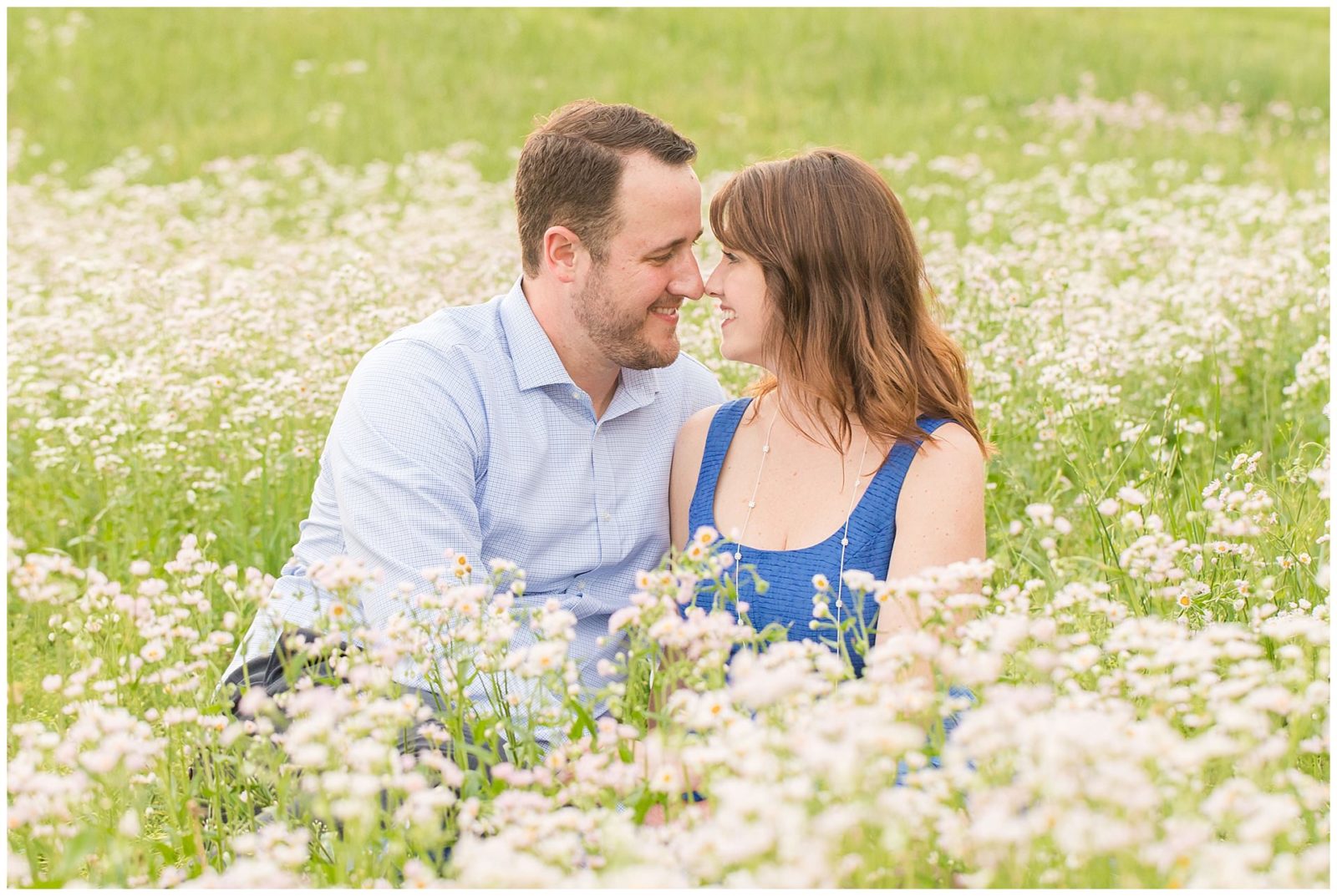 Couple sitting in a field of flowers during their engagement session at Shaker Village in Harrodsburg, KY